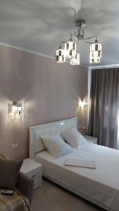 a bedroom with a large white bed and a chandelier at 1 кк люкс лофт студия in Mykolaiv