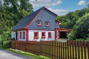 a small red and white house with a fence at Vlčihorská chaloupka in Krásná Lípa