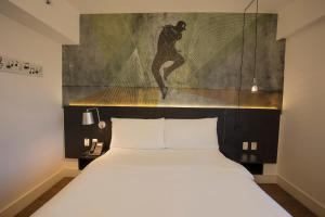 a bedroom with a bed and a painting on the wall at ibis Styles Taubate in Taubaté