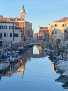 a bridge over a river with boats in a city at LAGUNA BLU Camera TRAMONTO con terrazza panoramica in comune in Chioggia