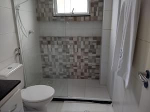 a bathroom with a toilet and a shower with a window at Cobertura Fort do Pontal in Arraial do Cabo