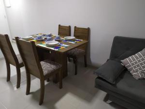 a dining room table with four chairs and a couch at Cobertura Fort do Pontal in Arraial do Cabo