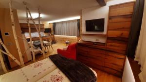 salon z telewizorem na komodzie z czerwoną kanapą w obiekcie Appartamento Cirmolo w mieście Peio