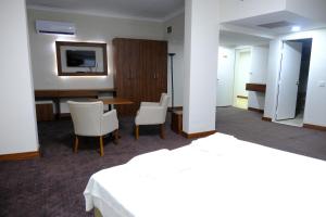 a hotel room with a desk and a table and chairs at Aksoy Otel in Adana