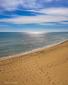 una spiaggia con impronte di piedi nella sabbia e nell'oceano di Casa vacanze Almàsalo a Noto Marina