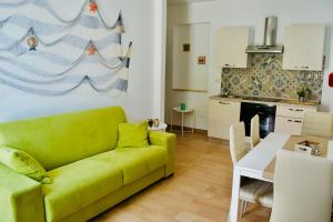 a living room with a green couch and a kitchen at Casa vacanze Almàsalo in Noto Marina