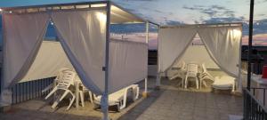 uma varanda com um monte de cadeiras e cortinas em Casa vacanze Almàsalo em Noto Marina