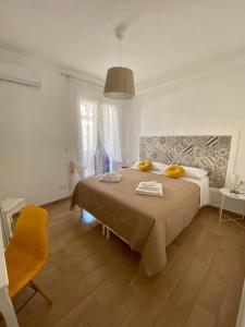 a bedroom with a large bed and a yellow chair at Casa vacanze Almàsalo in Noto Marina