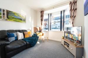 ハルにあるWGcDDE Large 3 Bedroom House - Close to MKM Stadium & A63 - Gardenのリビングルーム(黒い革張りのソファ、テレビ付)