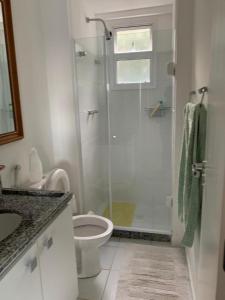 uma casa de banho branca com um chuveiro e um WC. em Porto Real Suítes Mangaratiba em Mangaratiba