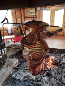 a piece of meat is cooking on a grill at Hostería Lago Cinco in Río Pico