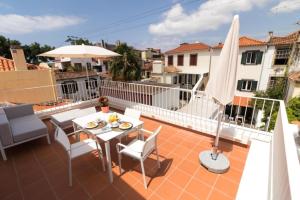 a balcony with a table and chairs and an umbrella at Welcome Madeira Apartments in Funchal