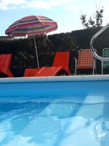 una piscina con sombrilla, sillas, mesa y sillas en Complejo Quimpe en Villa Giardino