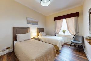 a hotel room with two beds and a chair at Park Lane Apartments/Shaw House in London