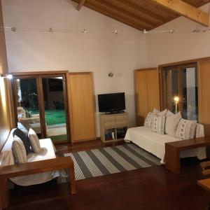 sala de estar con sofá blanco y TV en Casa dos Cinco - Gerês, en Terras de Bouro