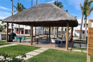 una sombrilla grande de paja con mesas y sillas en Nice House w/ shared pool and close to the beach at Mazatlan, en La Florida