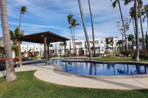 una piscina en un resort con palmeras en Nice House w/ shared pool and close to the beach at Mazatlan, en La Florida