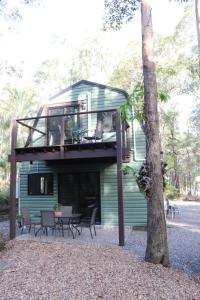 a house with a deck with a table and chairs at GREEN TREES CHALET 10 minutes to Australia Zoo Landsborough Montville Maleny Caloundra Beaches Glasshouse mountains Big Kart Track National forest in Landsborough