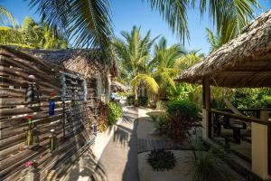 a resort with a wooden fence and palm trees at Caribbean Beach Cabanas in Placencia Village