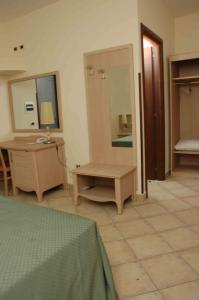 a room with a bed and a table and a mirror at Hotel Santa Rosa Centro Vacanze in Sangineto