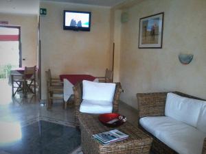 a living room with a couch and a tv on the wall at Hotel Santa Rosa Centro Vacanze in Sangineto