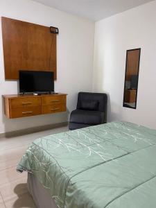 a bedroom with a bed and a chair and a tv at Palms Suites in Ciudad Acuña