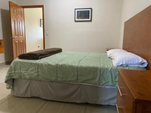 Un dormitorio con una cama con una manta verde. en CMG Suites, en Ciudad Acuña