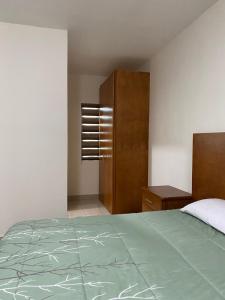 1 dormitorio con 1 cama y armario de madera en CMG Suites, en Ciudad Acuña