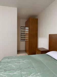 a bedroom with a bed and a wooden cabinet at Palms Suites in Ciudad Acuña