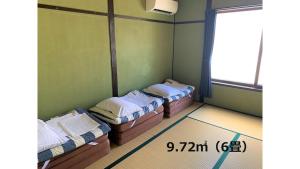 Cette chambre comprend 3 lits et une fenêtre. dans l'établissement Matsue Guesthouse, à Matsue