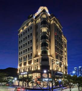 Un grand bâtiment avec des lumières allumées la nuit dans l'établissement AG405 Hotel, à Busan