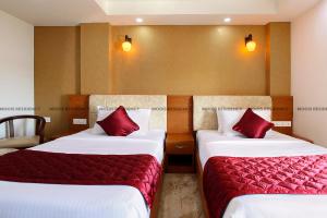 two beds in a hotel room with red pillows at Moois Residency in Kannur