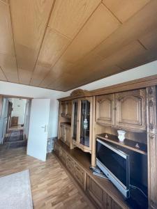 a kitchen with wooden cabinets and a flat screen tv at Vier Jahreszeiten 4JZ Haus 1 Whg 71 in Großenbrode