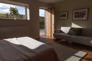 a living room with a bed and a couch and a window at "The Studio" Contemporary studio with organic swimming pool in Skelsmergh +16 photos