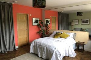 a bedroom with a white bed and orange walls at "The Studio" Contemporary studio with organic swimming pool in Skelsmergh