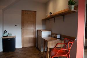 a kitchen with a wooden table and two red chairs at "The Studio" Contemporary studio with organic swimming pool in Skelsmergh