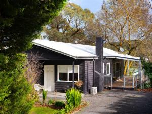 a small black house with a white door at The Apple Tree in Hepburn Springs