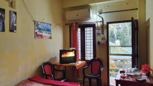 a room with a tv and a table with chairs at Ashavis Hotel Pvt Ltd in Māvelikara