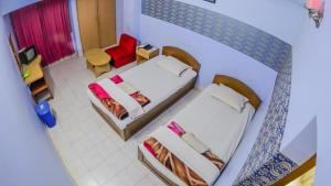 a small room with two beds and a red chair at HOTEL REGENT PARK in Chittagong