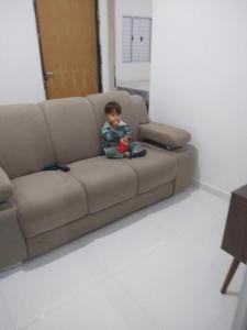 un petit garçon assis sur un canapé dans l'établissement Casa de praia no centro de Caraguatatuba, à Caraguatatuba