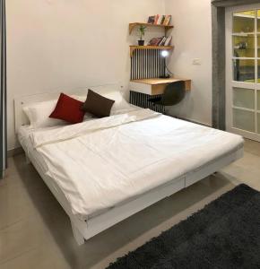 un letto bianco con cuscini rossi in una stanza di House 44 2BHK a Greater Noida