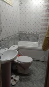 a bathroom with a toilet and a sink and a tub at Apartment Airkassa in Khujand