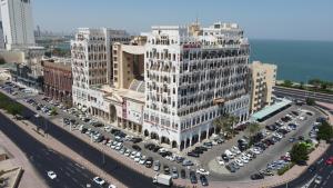 a large building with cars parked in a parking lot at Kuwait Palace Hotel in Kuwait