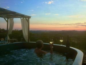 Un ragazzo in una vasca idromassaggio con un bicchiere di vino di Casapaletti Country House ad Alfiano Natta