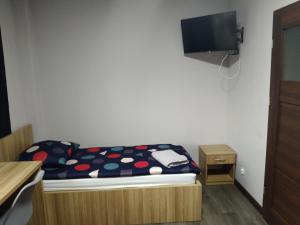 a small bedroom with a bed and a flat screen tv at Szafir - NoclegiGrodziskPL in Grodzisk Mazowiecki