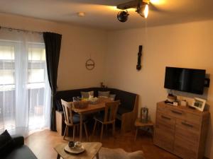 ein Wohnzimmer mit einem Tisch und einem TV in der Unterkunft Appartement Kuhglocken Ferienhaus Fuenf Sinne in Döbriach