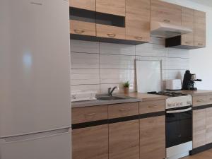 a kitchen with wooden cabinets and a sink and a stove at Tölgyerdő Apartman in Kismaros