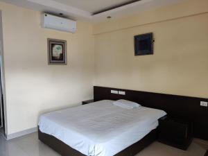 a bedroom with a large bed with white sheets at Fernandes Complex in Bangalore