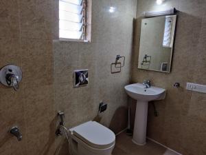 Un baño con lavabo, inodoro y espejo. en Fernandes Complex, en Bangalore