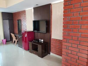 a room with a tv and a red brick wall at Fernandes Complex in Bangalore